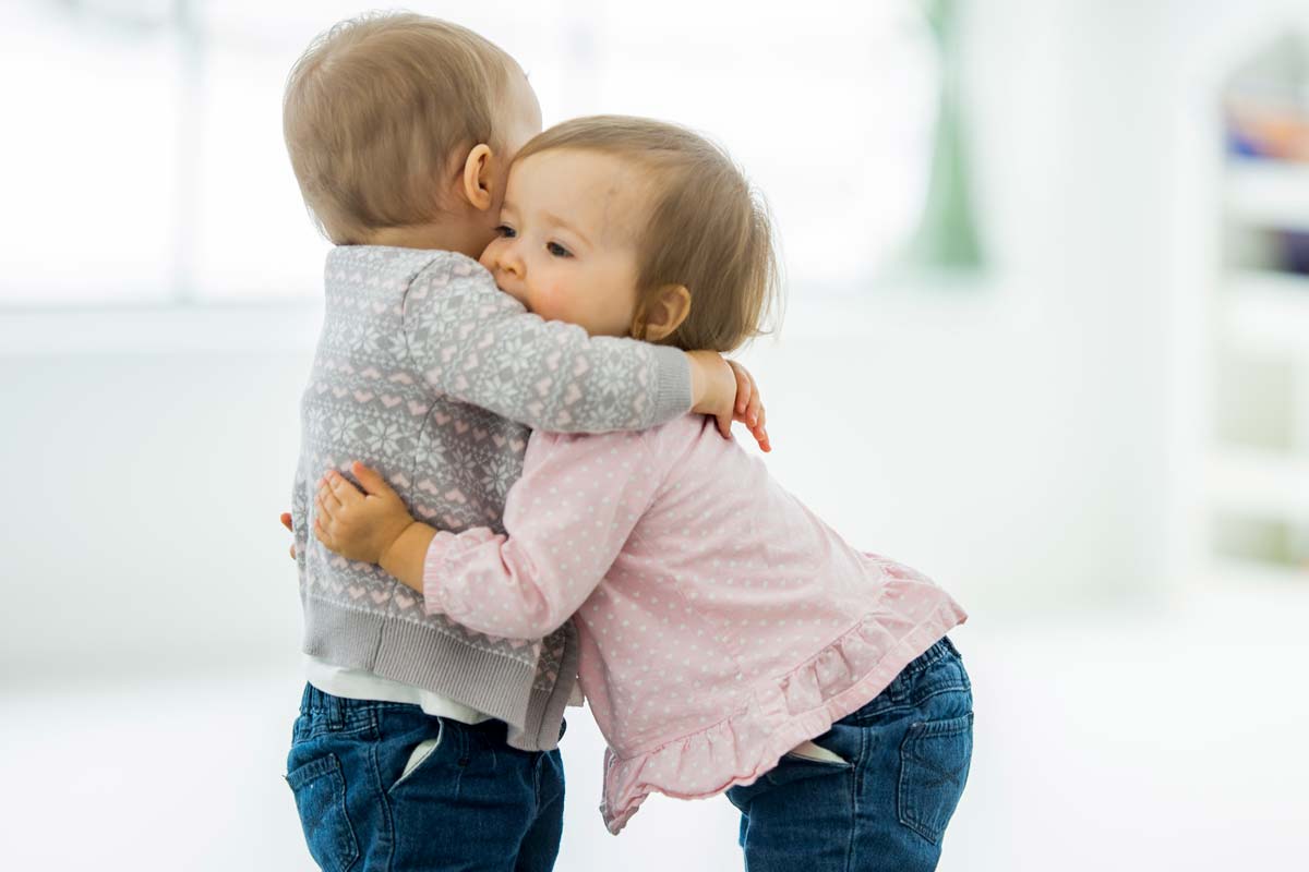 Två små barn ger varandra en kram.